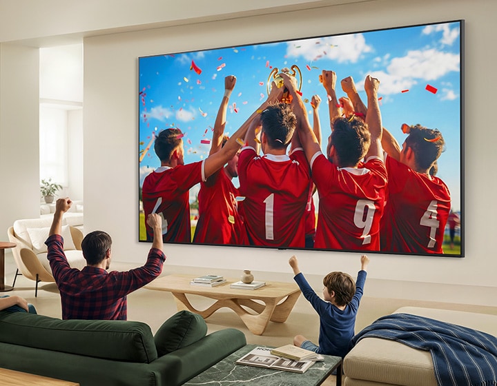 LG QNED evo AI QNED85 Mini LED Ultra Big TV на стене в гостиной, семья празднует победу в спортивном состязании